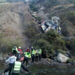 Vehículo queda destrozado en una zona montañosa mientras equipos de rescate trabajan en un barranco de difícil acceso